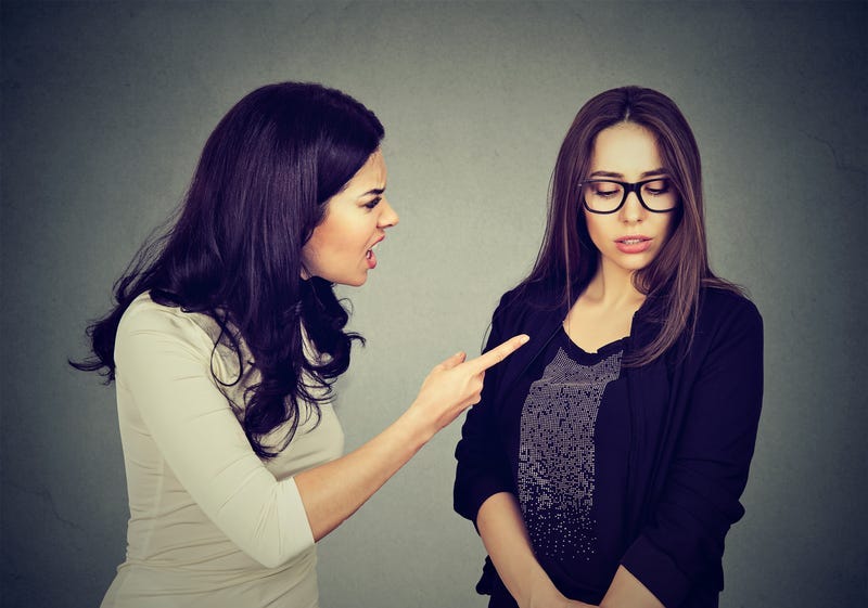 Angry woman scolding her scared shy sister or friend.