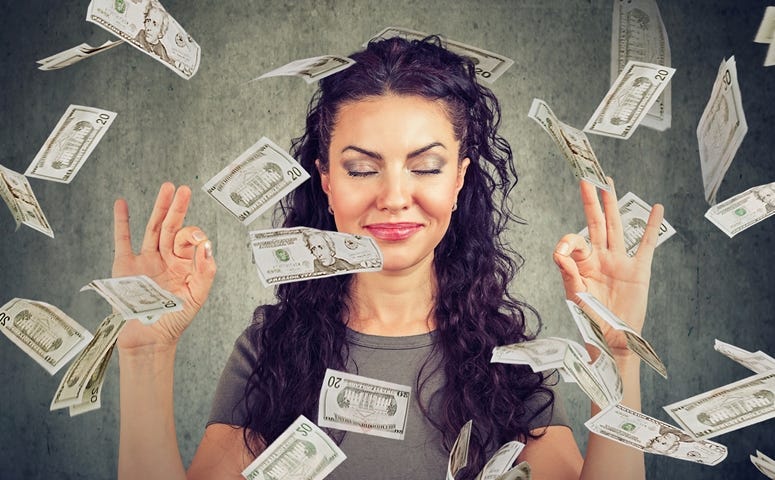 Woman meditating under money rain