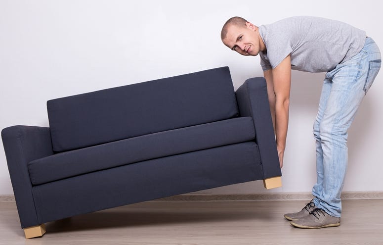 Young man lifting up sofa or couch