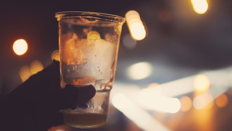a person holds up an empty cup of beer