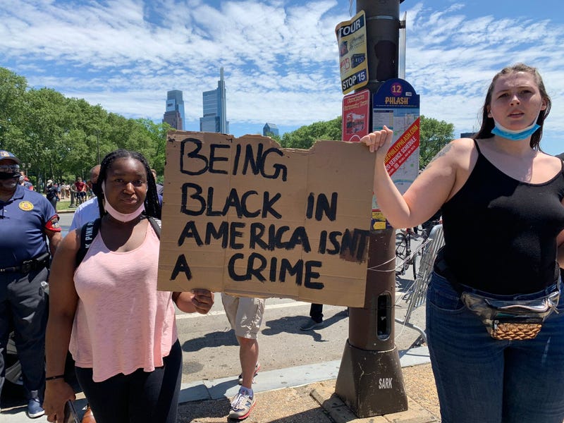 A pair of demonstrators holding a sign at the Philadelphia Museum or Art Saturday afternoon. The planned protests began peacefully, but erupted into violence after marchers left the Art Museum.