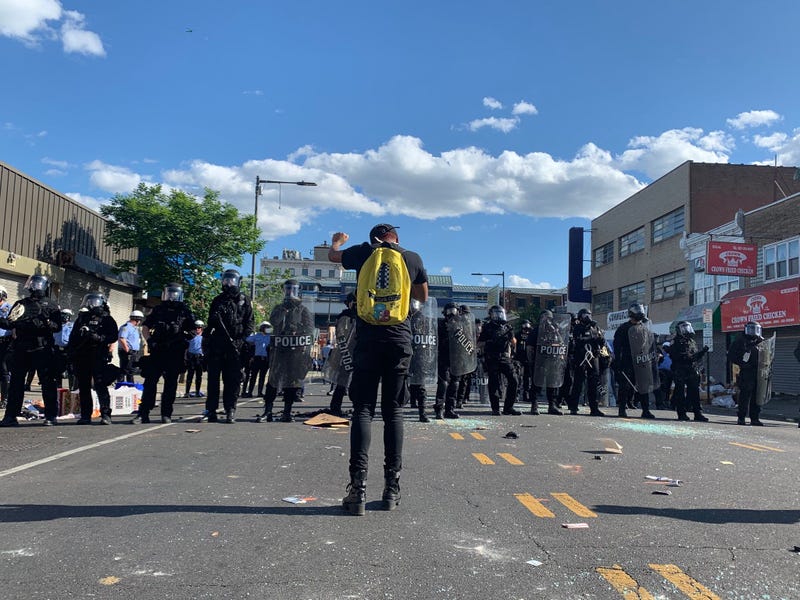 A line of police officers are confronted by a single protester in West Philly.