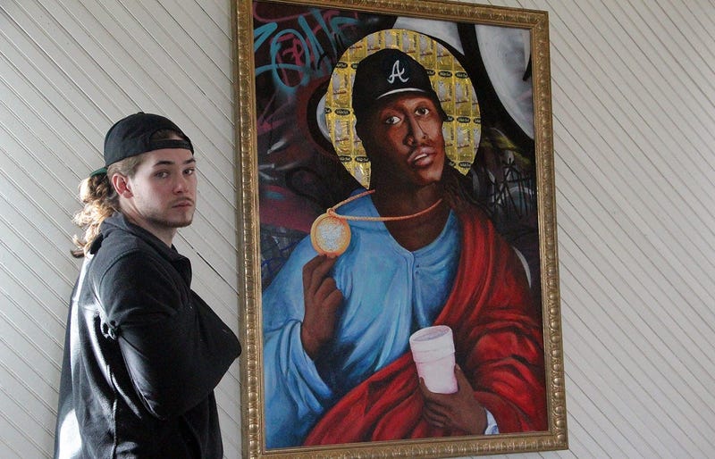 FREEKYBEAR stands next to his painting of Future at the TRAP CHAPEL pop-up art gallery in Atlanta