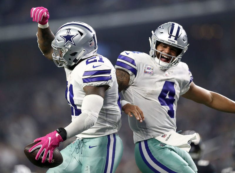 Ezekiel Elliott #21 and Dak Prescott #4 of the Dallas Cowboys celebrate the fourth quarter touchdown against the Jacksonville Jaguars at AT&T Stadium on October 14, 2018 in Arlington, Texas.