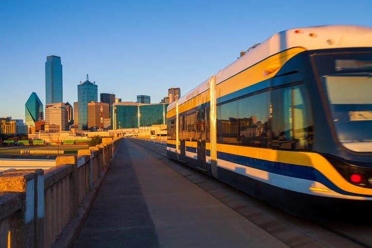 Moving streetcar on the Houston Street Viaduct with the city of Dallas in background