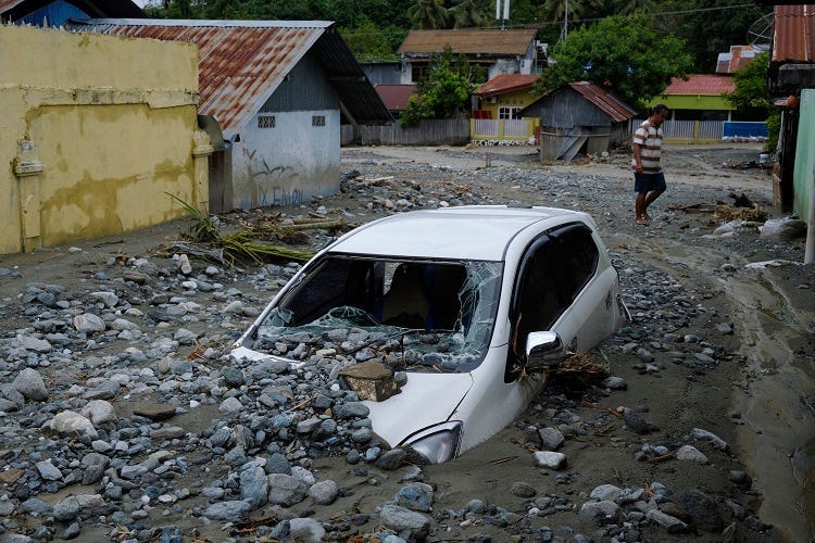 A car sits abandoned in the mud on a flooded street on March 20, 2019 in Sentani, Papua province, Indonesia. At least 104 people have died and nearly 7,000 have been displaced from their homes after three straight days of heavy rain led to massive flash