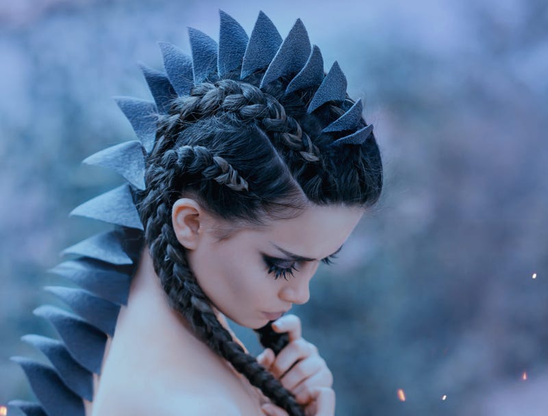 Dragon girl Black, sharp thorns cover the back and head of a young woman. Creative fabulous image of an alien humanoid creature. Unusual hairstyle with braids. Gothic dark makeup. Art retouching.