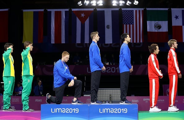 Gold medalist Race Imboden of United States takes a knee during the National Anthem Ceremony in the podium of Fencing Men's Foil Team Gold Medal Match Match on Day 14 of Lima 2019 Pan American Games at Fencing Pavilion of Lima Convention Center on August