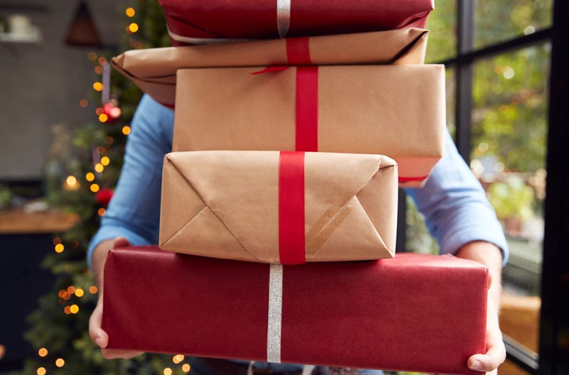 A man holds a stack of packages that obscure his face