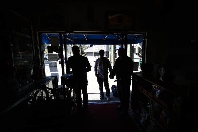 Akber Jiwani (R), the owner of New Bait Shop, and David Johnson (L), owner of Davey Jones Market, talk to a customer in front of their store darkened by a power outage on October 10, 2019 in Sausalito, California.