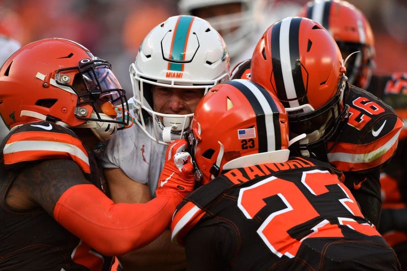 CLEVELAND, OH - NOVEMBER 24: Patrick Laird #42 of the Miami Dolphins drags Mack Wilson #51 of the Cleveland Browns, far left, Damarious Randall #23 of the Cleveland Browns and Greedy Williams #26 of the Cleveland Browns for a first down near the goal line