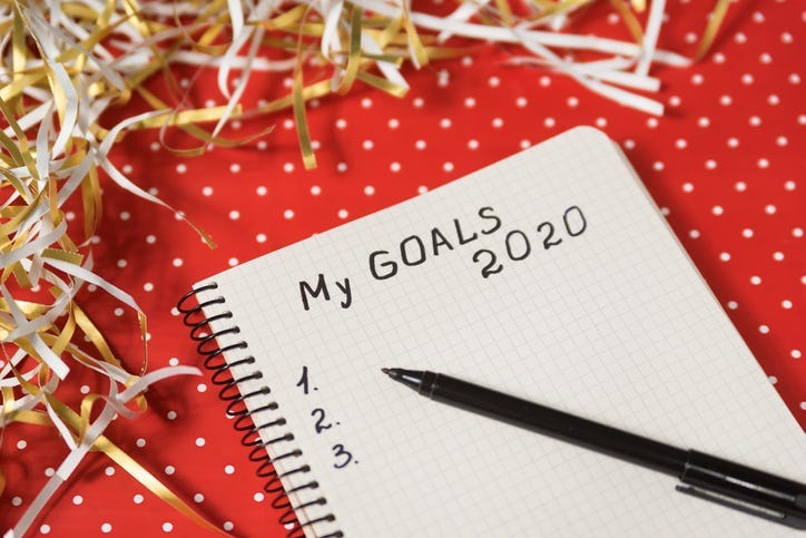 Phrase My Goals 2020 in a notebook, black pen. Red background and tinsel. New Years concept