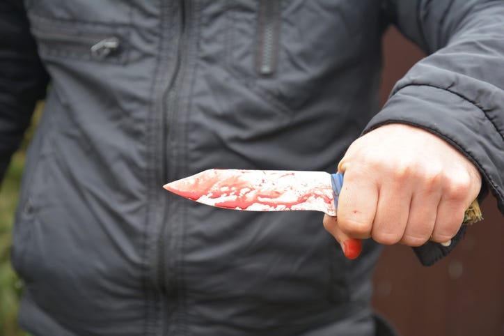 Knife attack concept. Murderer, killer is attacking with knife with red fake blood drops.