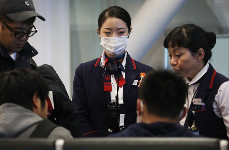 A Japan Airlines worker (C) wears a face mask while working inside a terminal at Los Angeles International Airport on Jan. 23, 2020. 