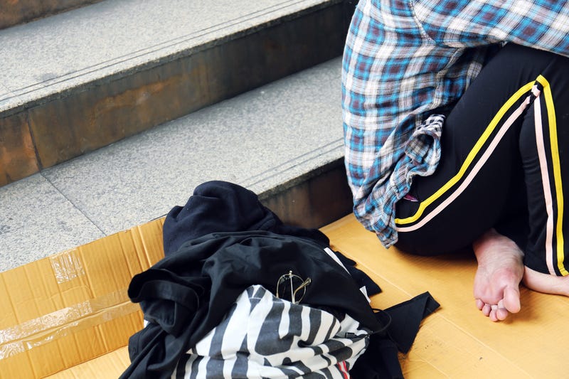 Senior homeless man sitting on walking street