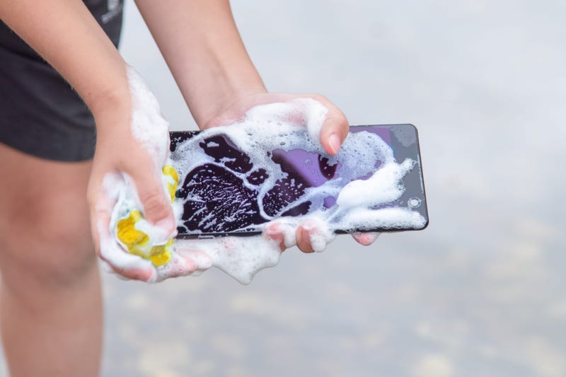 cell phone in hands is wet and covered in foam