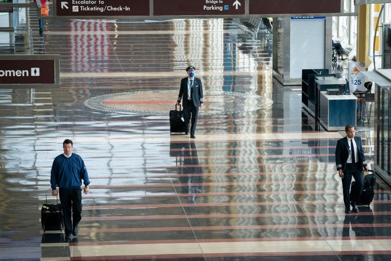 A pilot wears a face covering as he walks through a mostly empty terminal at Ronald Reagan Washington National Airport.