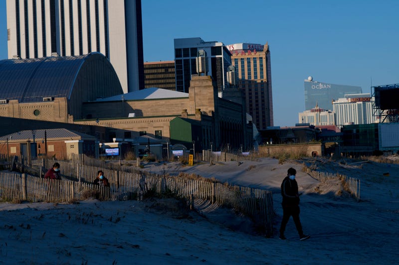 People wearing masks walk on the beach at dusk during the coronavirus pandemic on May 7, 2020 in Atlantic City, New Jersey.