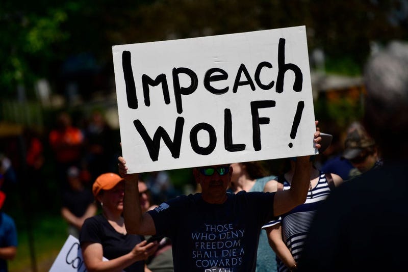 A demonstrator holds a sign stating "Impeach Wolf!" during a protest rally against Pennsylvania Governor Tom Wolf outside the State Capitol Building