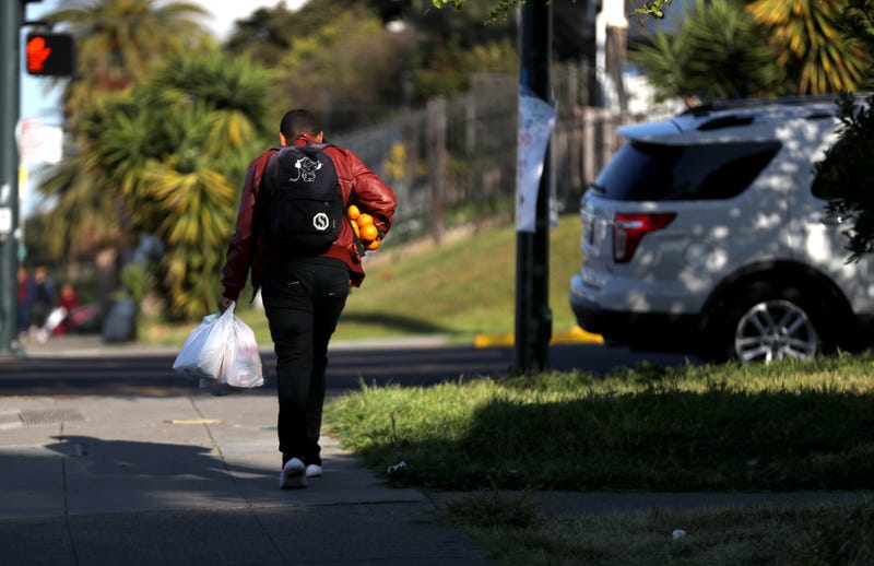 A man carries oranges and a bag of food that he received from the faculty at Garfield Elementary School on March 19, 2020 in Oakland.