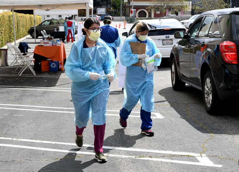 Workers wearing personal protective equipment gather COVID-19 tests administered in Los Angeles