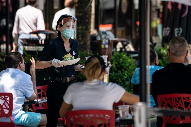 A waiter at Raku, an Asian restaurant in Bethesda, wears a protective face mask as serve customers outdoors amid the coronavirus pandemic on June 12, 2020 in Bethesda, Maryland.
