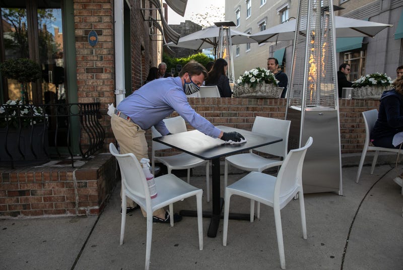 An employee at Terra restaurant cleans an outdoor table on May 20, 2020 in Greenwich, Connecticut.