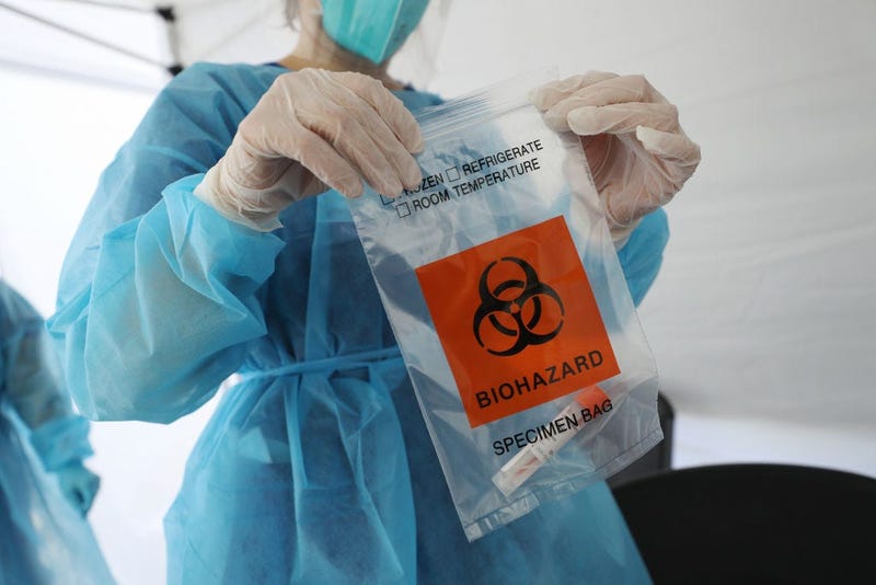 A nurse seals a specimen bag containing a COVID-19 test swab at a St. John’s Well Child & Family Center mobile clinic