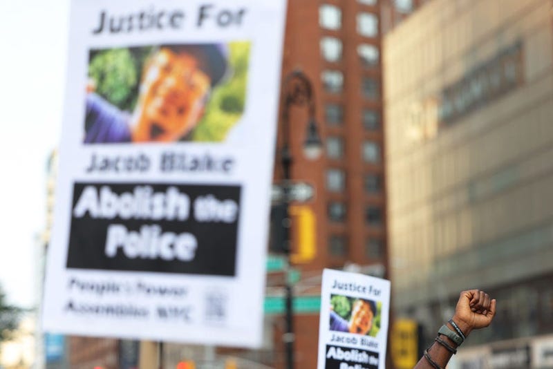 Demonstrators raise signs and their fist as they gather for a vigil for Jacob Blake on August 25, 2020 in New York City.