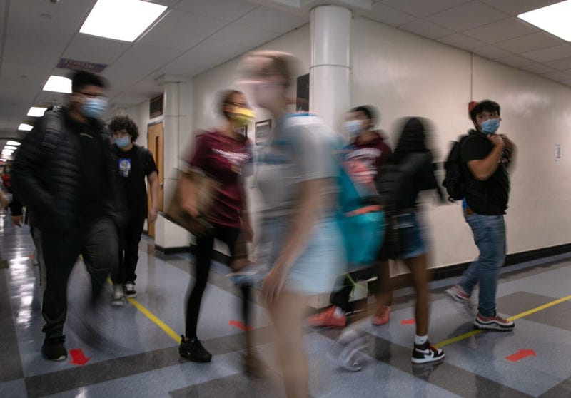 Masked students walk the halls between classes during the first day of school