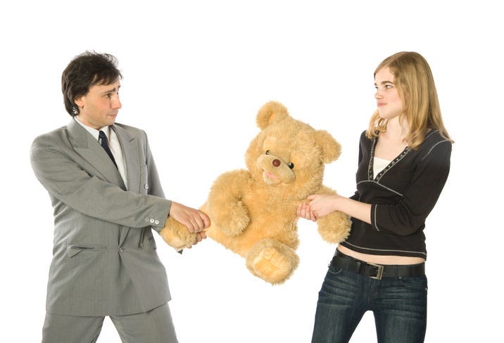Young man and woman fighting over a teddy-bear