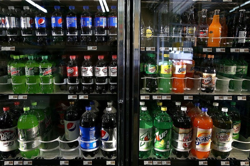 Various bottles of soda are displayed in a cooler.
