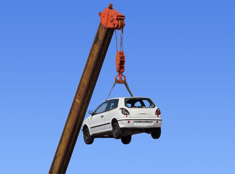 White car hanging by the arm of a crane