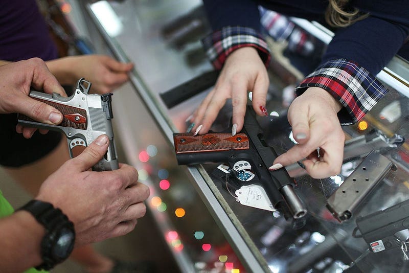POMPANO BEACH, FL - DECEMBER 23: A customer compares handguns before buying one as a Christmas present at the National Armory gun store on December 23, 2015 in Pompano Beach, Florida.