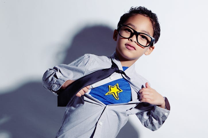 Adorable mixed race boy ripping off his dress shirt to uncover his superhero costume underneath.