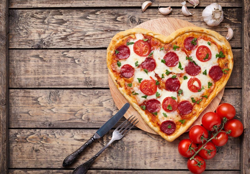 Heart shaped pizza with pepperoni, tomatoes and mozzarella on vintage - stock photo