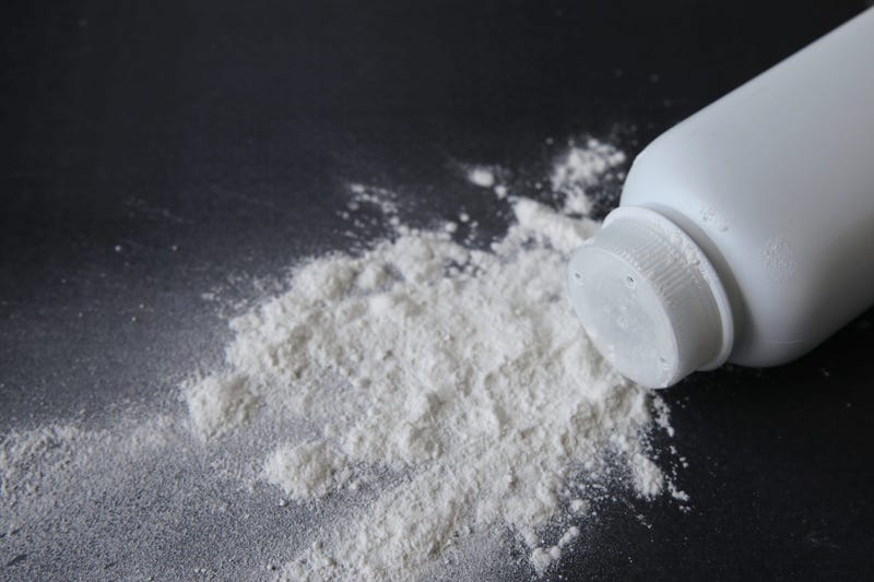 A container of talcum powder is spilled on a black background