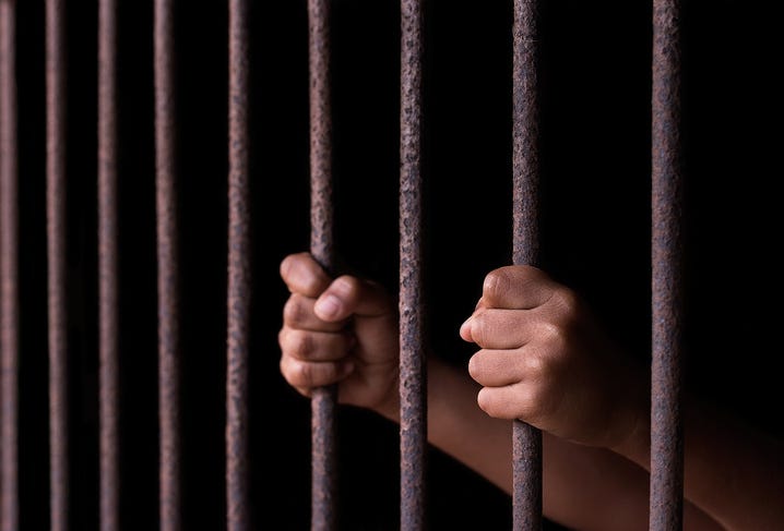 Hands on prison bars