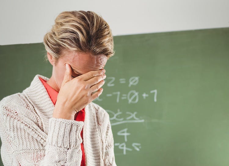 Teacher crying in front of blackboard at school