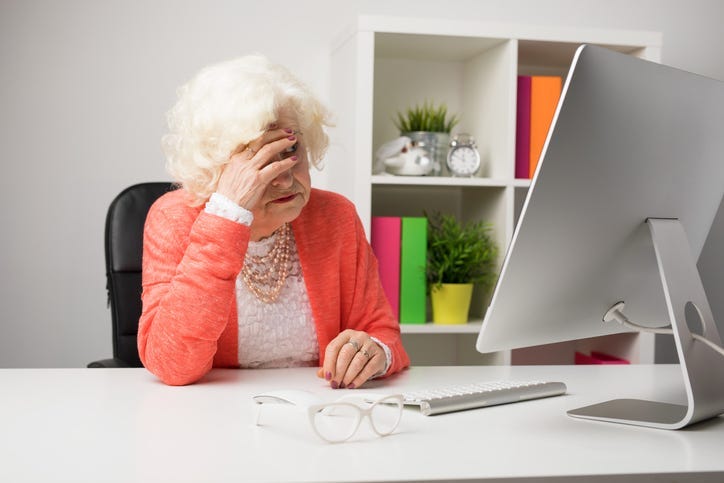 Older woman working at the office and having headache