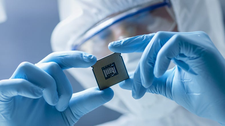Design Engineer in Sterile Coverall Holds Microchip with Gloves