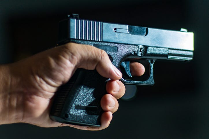 Man's hand holding a handgun on black