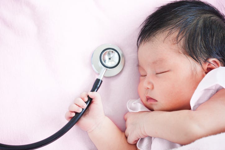Cute asian newborn baby girl sleeping and holding medical stethoscope in hand