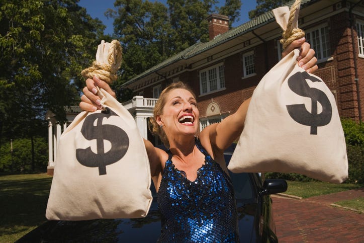 Woman with money bags in front of mansion - stock photo