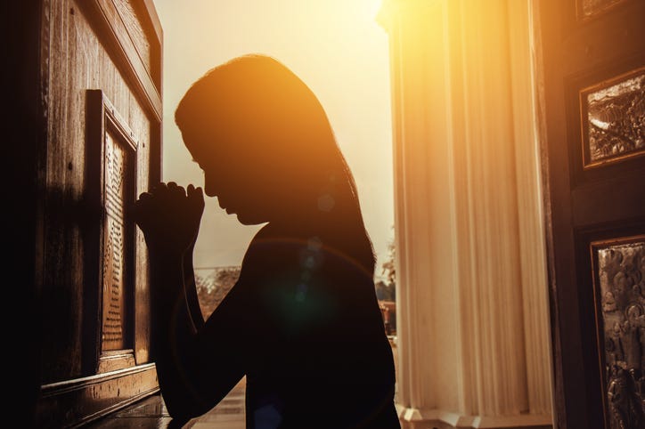silhouette of woman kneeling and praying