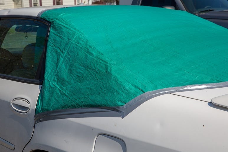 Green tarp covers back window to protect from the elements