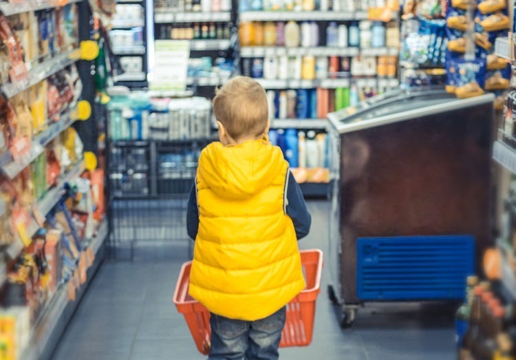 Back view of kid buying groceries at supermarket.