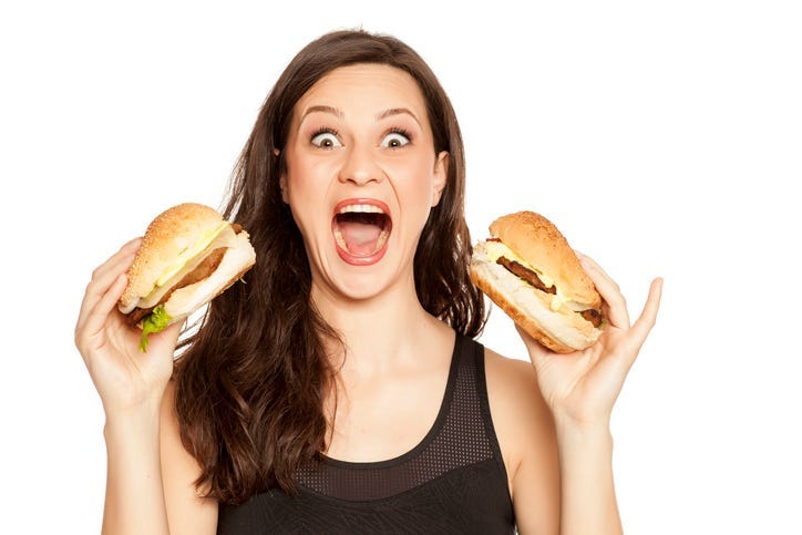 young beautiful greedy woman holding two burgers on white background