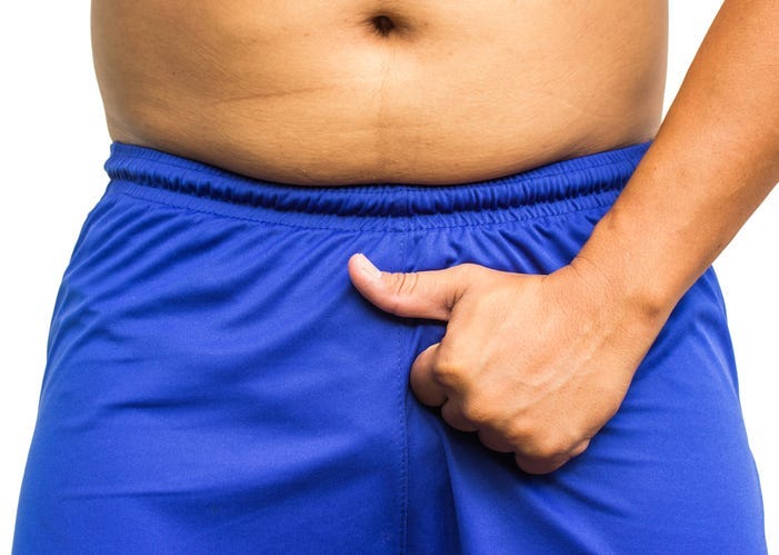 man holding his penis in his shorts, showing thumb up. No problems in the potency
