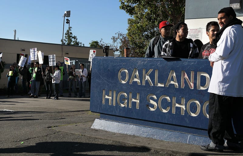 Students look on as teachers hold signs while they protest during a one-day strike outside of Oakland High School April 29, 2010 in Oakland, California.